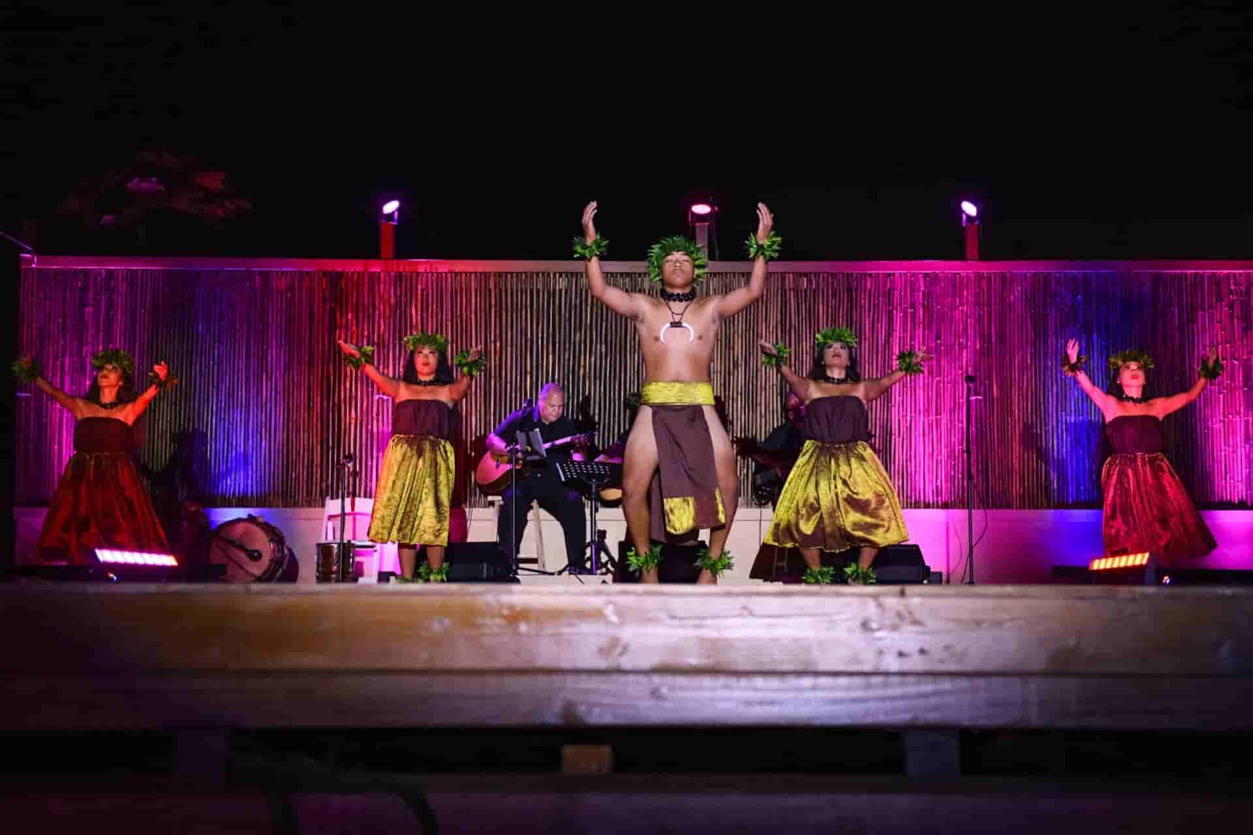 Kahiko hula dancers under pink stage light at a private Kauai event